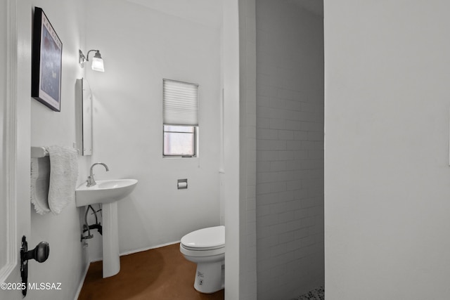 full bathroom with toilet, baseboards, and tiled shower