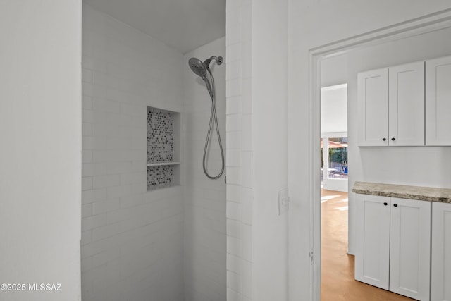 full bath featuring a tile shower and vanity