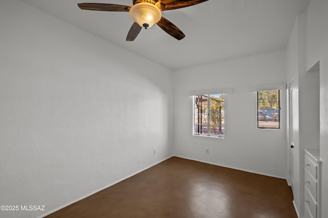 spare room with baseboards, concrete flooring, and a ceiling fan