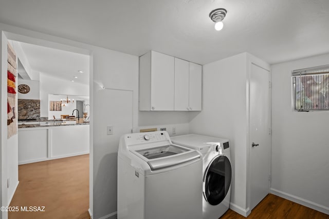 laundry room with washing machine and clothes dryer, baseboards, a chandelier, wood finished floors, and cabinet space