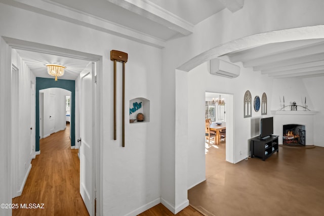 hall with baseboards, a wall mounted AC, beam ceiling, arched walkways, and a chandelier