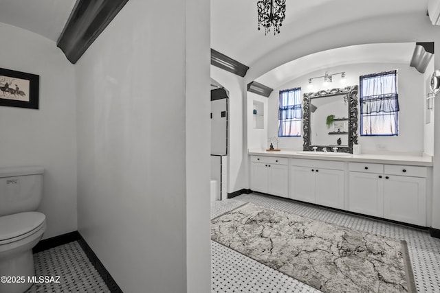 bathroom featuring baseboards, toilet, lofted ceiling, and vanity