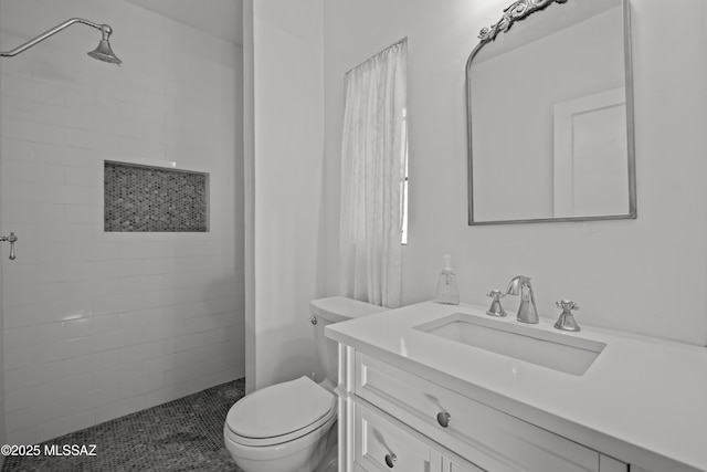 full bathroom featuring vanity, toilet, and a tile shower