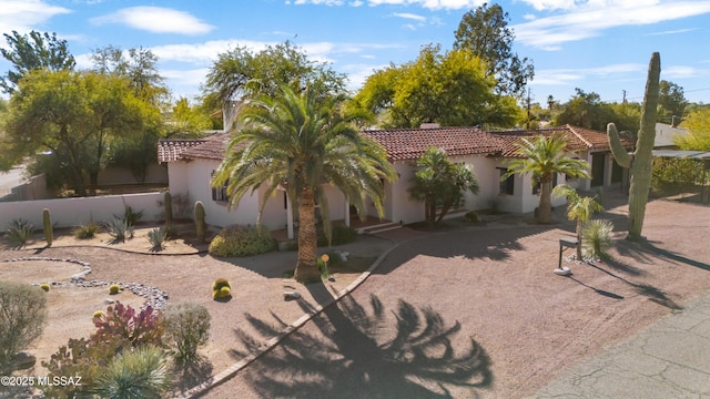 mediterranean / spanish-style home with stucco siding, fence, and a tiled roof