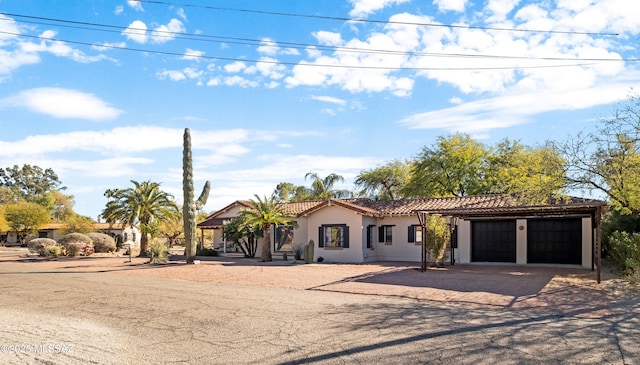 mediterranean / spanish-style house featuring a tiled roof, an attached garage, driveway, and stucco siding