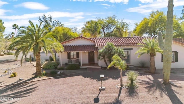 mediterranean / spanish-style home featuring a tile roof, a porch, and stucco siding