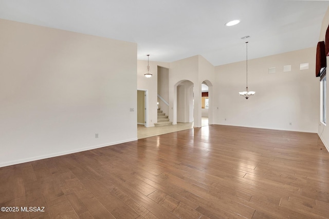 unfurnished living room with high vaulted ceiling, a notable chandelier, and light hardwood / wood-style flooring