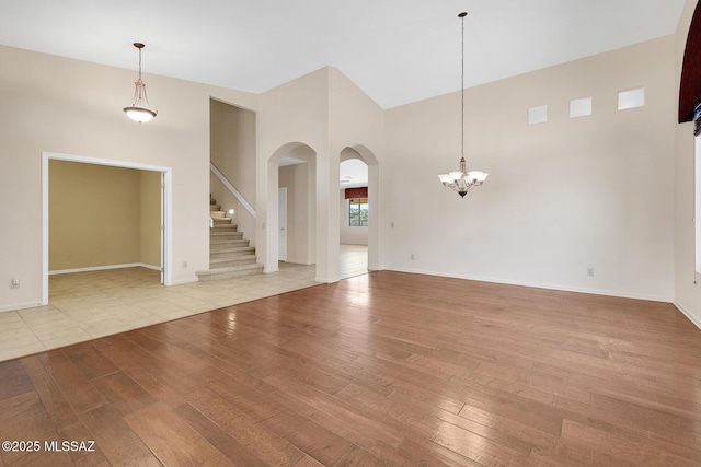 unfurnished living room with light hardwood / wood-style floors, a high ceiling, and a chandelier