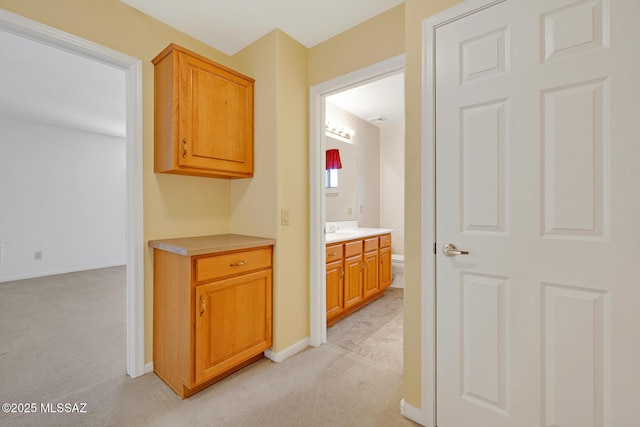 hallway featuring sink and light carpet