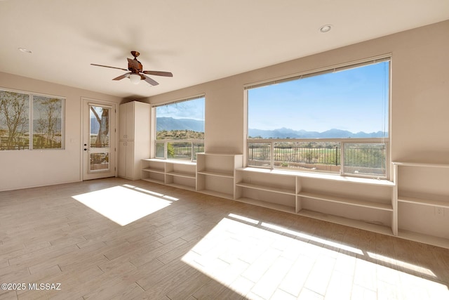 unfurnished sunroom with ceiling fan and a mountain view