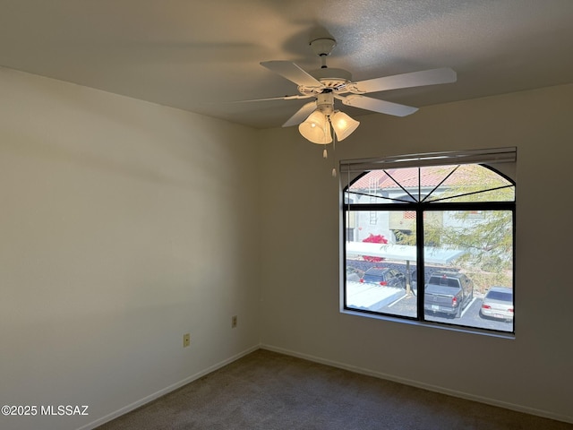 carpeted empty room with a ceiling fan and baseboards