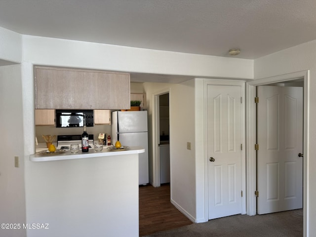 kitchen featuring dark carpet, kitchen peninsula, light brown cabinetry, white fridge, and range