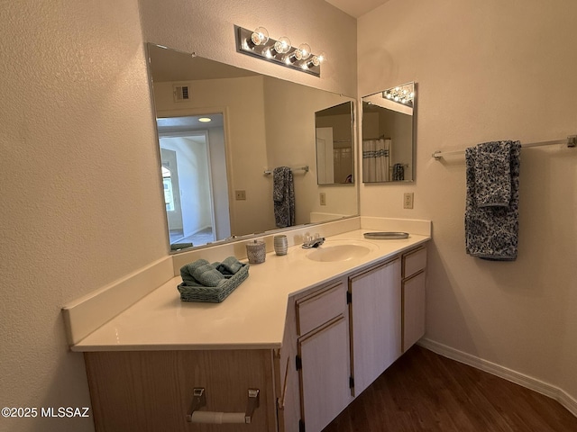 bathroom with vanity, baseboards, and wood finished floors