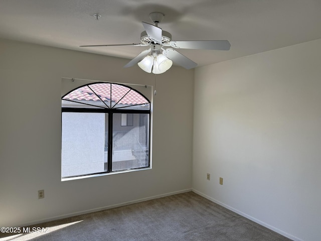 carpeted spare room featuring baseboards and ceiling fan