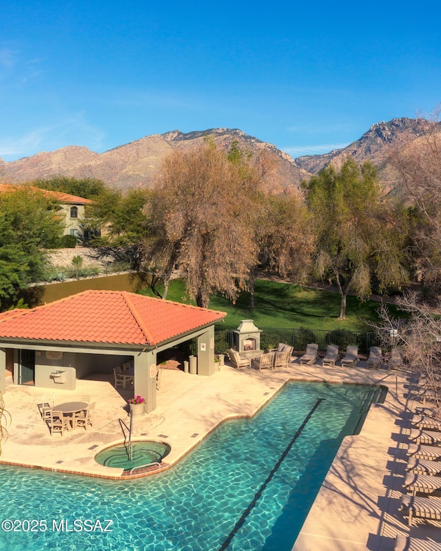 community pool featuring a mountain view, a hot tub, a patio, and fence