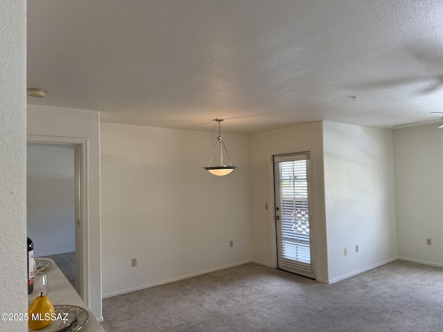 carpeted empty room featuring a textured ceiling and baseboards