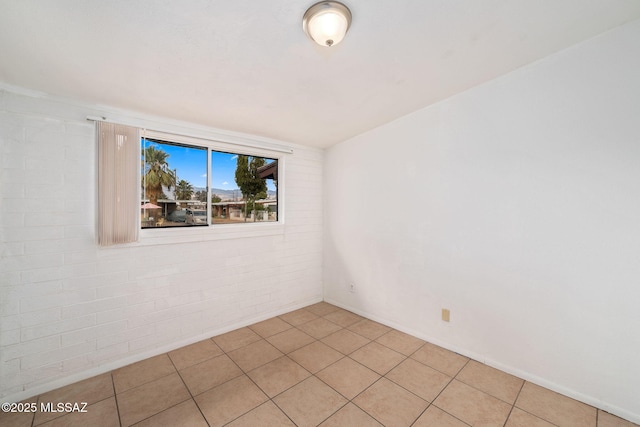 tiled empty room featuring brick wall