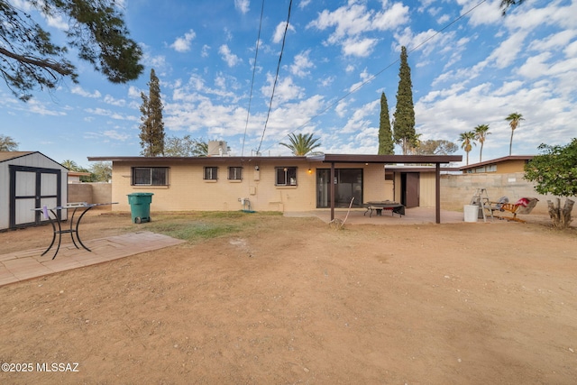 rear view of house with a patio area and a shed