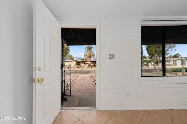 entrance foyer with plenty of natural light, light tile patterned floors, and brick wall