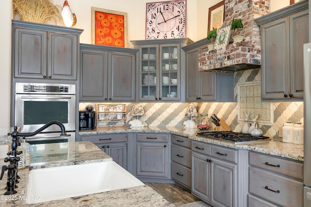 kitchen featuring backsplash, sink, gray cabinets, appliances with stainless steel finishes, and custom range hood