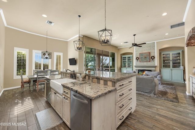 kitchen with a kitchen island with sink, sink, ceiling fan, dark hardwood / wood-style floors, and a fireplace