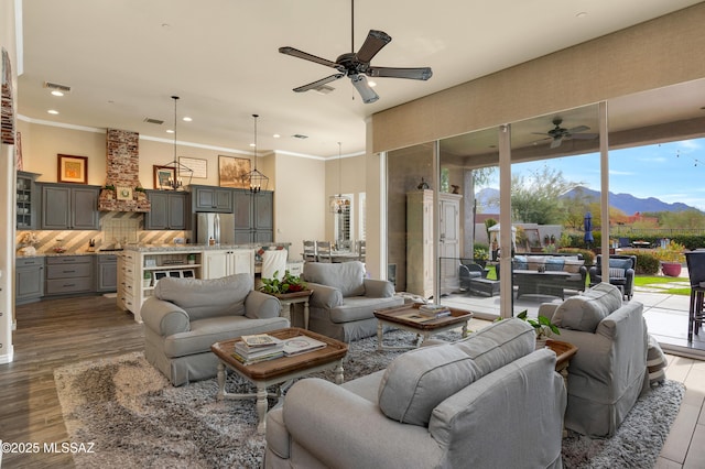 living room with a mountain view, ceiling fan, and light wood-type flooring