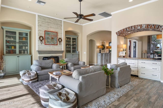 living room with ceiling fan, wood-type flooring, and crown molding