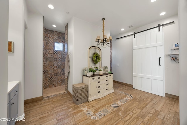 interior space with a barn door, light hardwood / wood-style floors, and a chandelier