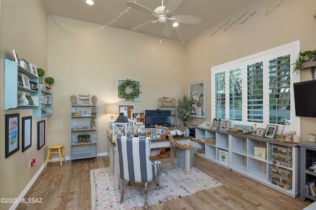 office space featuring wood-type flooring, a towering ceiling, and ceiling fan