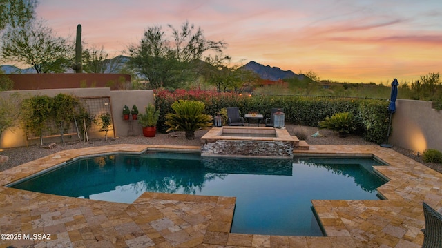 pool at dusk with a patio area, an in ground hot tub, and a mountain view