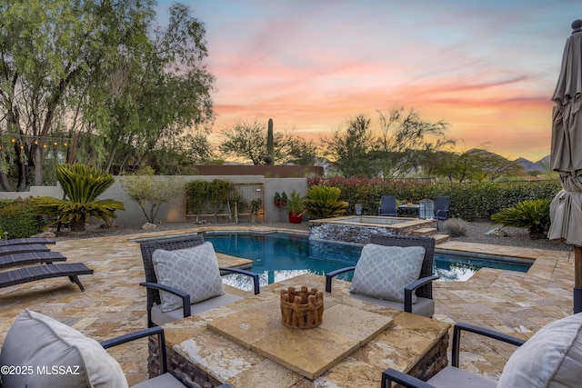 pool at dusk with an in ground hot tub and a patio