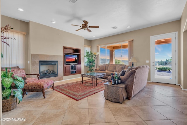 living room with ceiling fan, light tile patterned floors, and a tiled fireplace