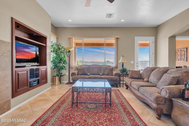 tiled living room featuring ceiling fan and built in features