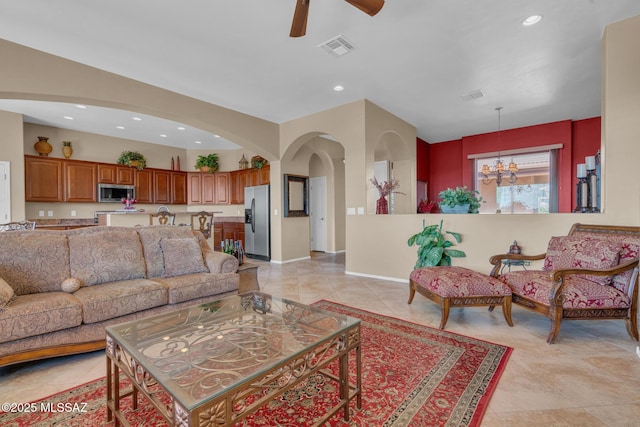 living room featuring light tile patterned floors and ceiling fan with notable chandelier