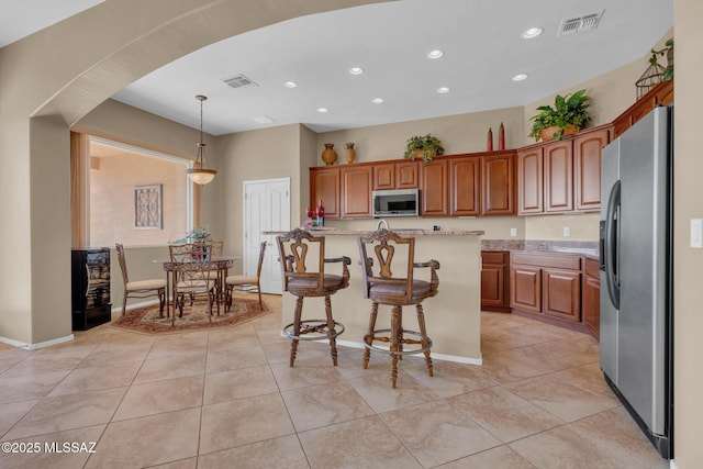 kitchen with decorative light fixtures, light tile patterned flooring, stainless steel appliances, and a center island