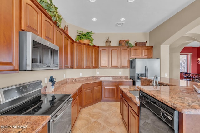 kitchen with light tile patterned floors, stainless steel appliances, and light stone counters