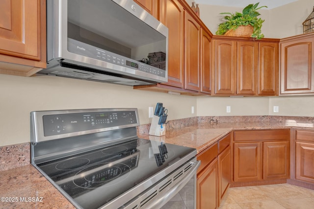 kitchen featuring light tile patterned floors, light stone counters, and stainless steel appliances