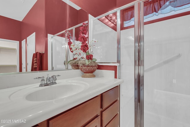 bathroom featuring a shower with door and vanity