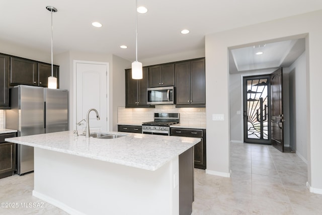 kitchen featuring dark brown cabinets, stainless steel appliances, hanging light fixtures, and a center island with sink