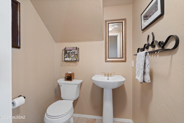 bathroom featuring sink, lofted ceiling, toilet, and tile patterned flooring