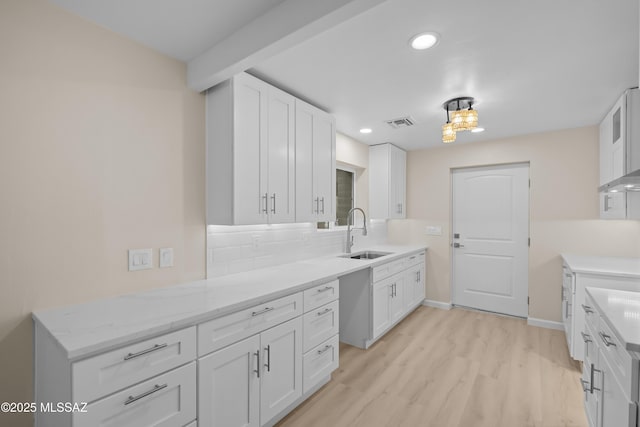 kitchen featuring light hardwood / wood-style flooring, sink, decorative backsplash, and white cabinets