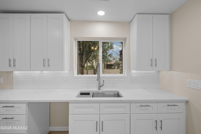 kitchen with tasteful backsplash, sink, and white cabinets