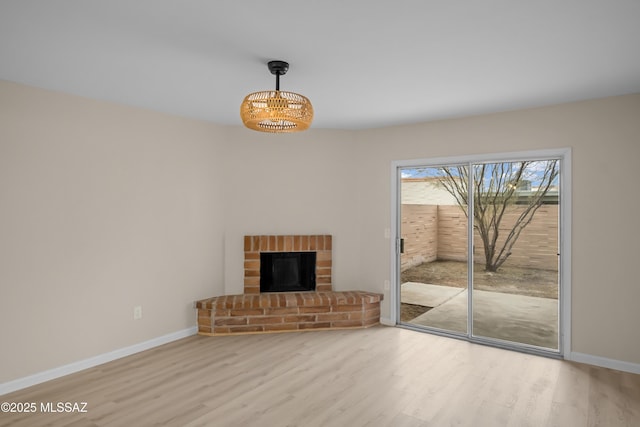 unfurnished living room with a brick fireplace and light hardwood / wood-style floors