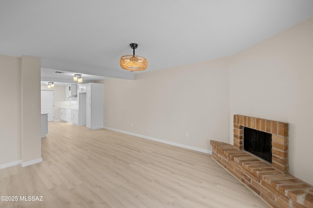 unfurnished living room featuring a brick fireplace and light wood-type flooring