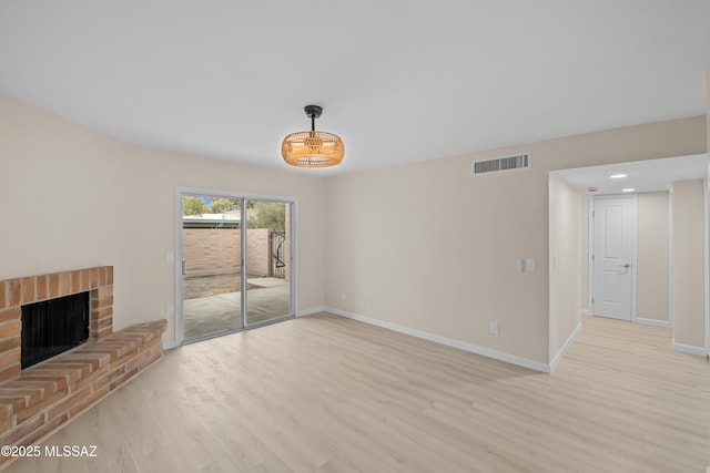 unfurnished living room with a brick fireplace and light hardwood / wood-style flooring