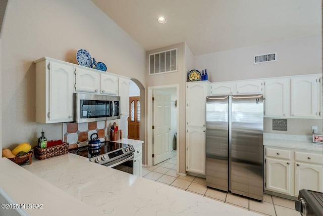 kitchen featuring white cabinets, appliances with stainless steel finishes, high vaulted ceiling, and light tile patterned floors