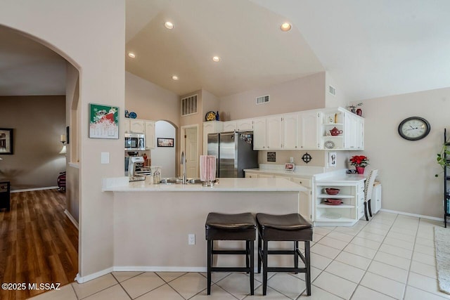 kitchen featuring white cabinetry, sink, stainless steel appliances, kitchen peninsula, and a breakfast bar