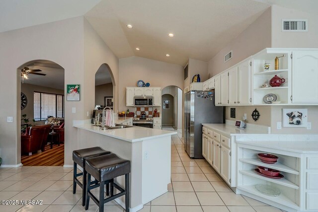 kitchen with appliances with stainless steel finishes, vaulted ceiling, light tile patterned floors, and sink