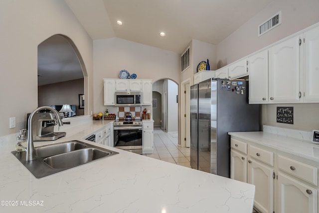 kitchen with sink, kitchen peninsula, lofted ceiling, white cabinets, and appliances with stainless steel finishes