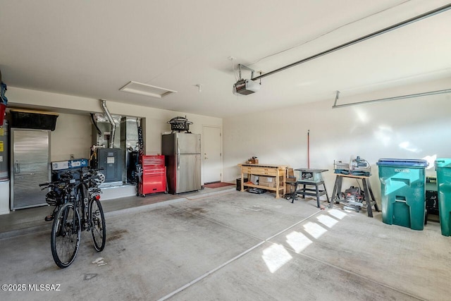 garage with stainless steel fridge, a garage door opener, and heating unit